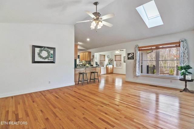 unfurnished living room with a ceiling fan, light wood-style flooring, and baseboards