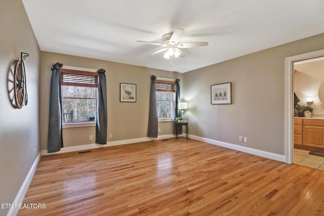 empty room featuring baseboards, light wood-type flooring, and a healthy amount of sunlight