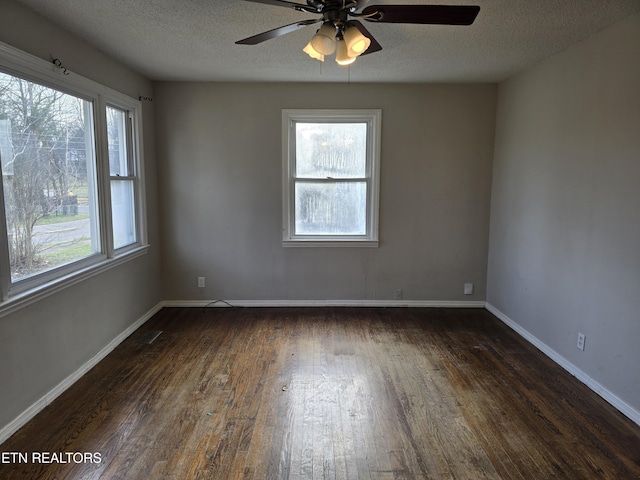 spare room with dark wood-style floors, visible vents, baseboards, and a textured ceiling