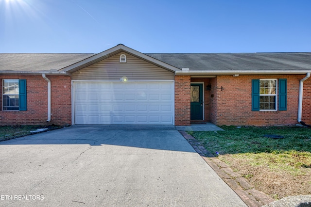 single story home with a front lawn, concrete driveway, brick siding, and an attached garage