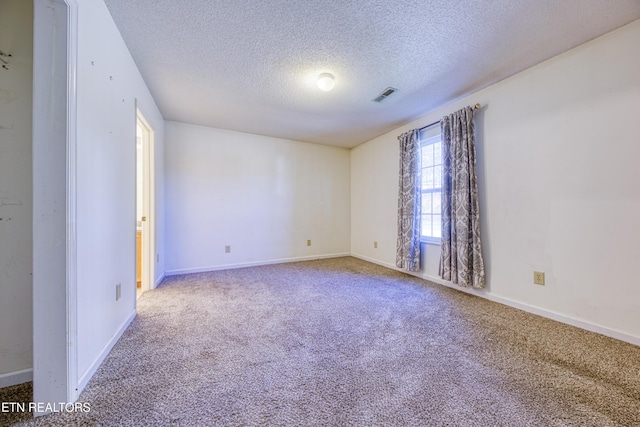 carpeted spare room featuring visible vents, a textured ceiling, and baseboards