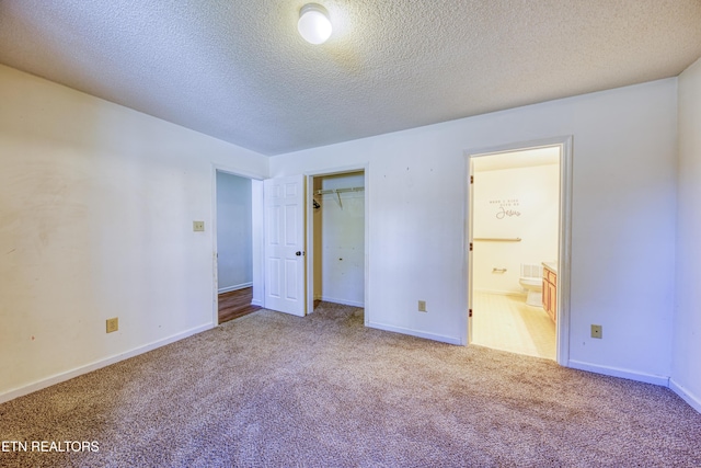 unfurnished bedroom with a closet, carpet flooring, connected bathroom, a textured ceiling, and baseboards