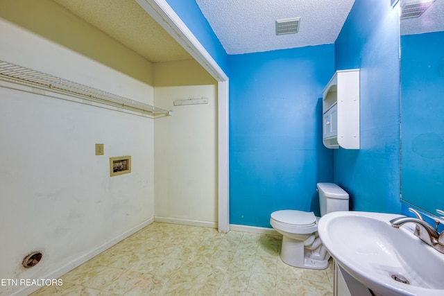 bathroom with baseboards, visible vents, toilet, a textured ceiling, and a sink