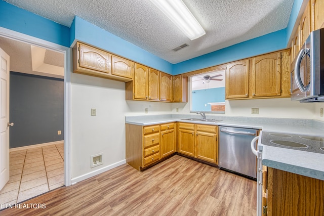 kitchen featuring visible vents, appliances with stainless steel finishes, brown cabinets, light countertops, and a sink