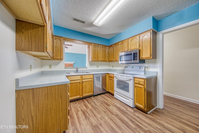 kitchen featuring light wood-style floors, appliances with stainless steel finishes, light countertops, and brown cabinetry