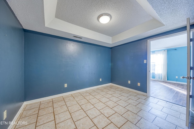 spare room with visible vents, baseboards, a raised ceiling, and a textured ceiling