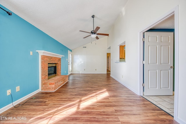 unfurnished living room featuring a fireplace, light wood-style flooring, a ceiling fan, a textured ceiling, and baseboards