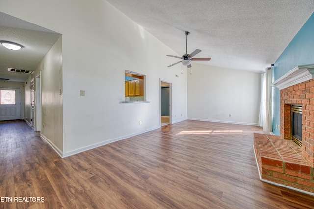 unfurnished living room with lofted ceiling, a fireplace, visible vents, and wood finished floors