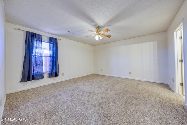 spare room with a textured ceiling, carpet floors, visible vents, baseboards, and a ceiling fan