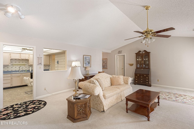 living room featuring light colored carpet, sink, vaulted ceiling, ceiling fan, and a textured ceiling