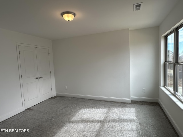 unfurnished bedroom with dark carpet and a closet
