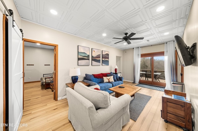 living room featuring a barn door, light wood-type flooring, and ceiling fan