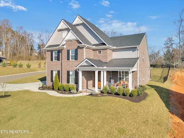 view of front of home featuring brick siding, a front lawn, fence, covered porch, and metal roof