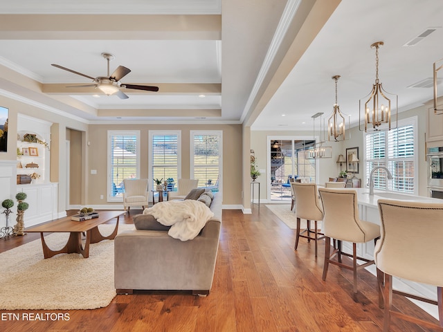 living room featuring visible vents, wood finished floors, crown molding, and ceiling fan with notable chandelier