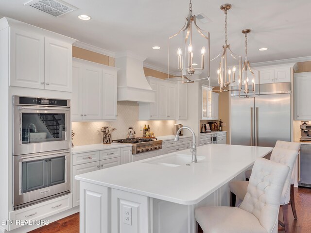 kitchen featuring visible vents, ornamental molding, custom range hood, a sink, and stainless steel appliances