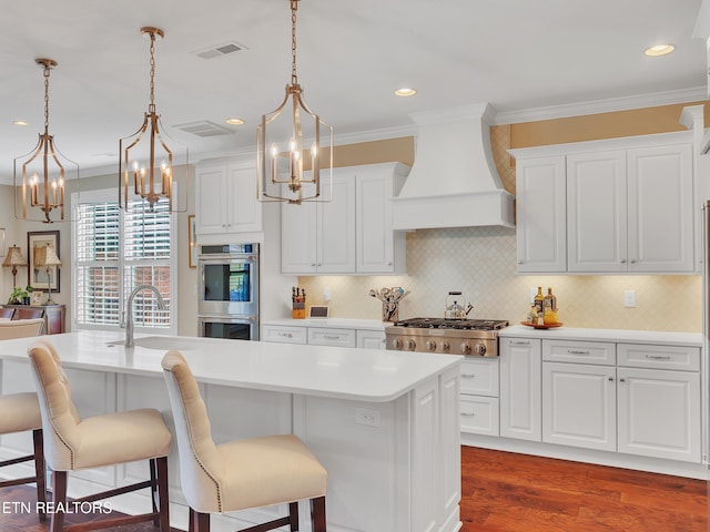 kitchen featuring visible vents, crown molding, custom exhaust hood, stainless steel appliances, and a sink