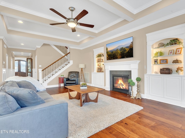 living room featuring wood finished floors, recessed lighting, ornamental molding, stairs, and a glass covered fireplace