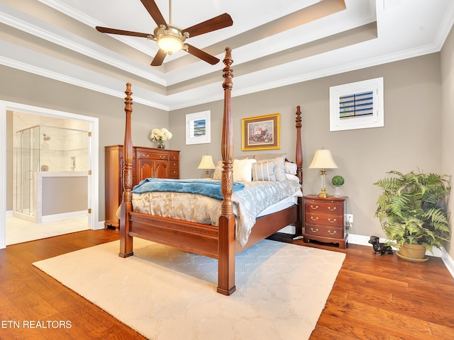 bedroom featuring ornamental molding, baseboards, a tray ceiling, and wood finished floors