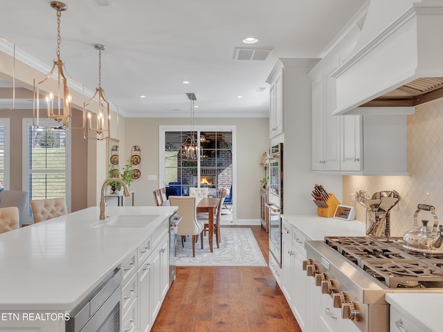 kitchen featuring visible vents, a sink, crown molding, custom exhaust hood, and stainless steel gas cooktop