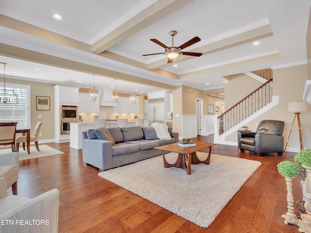 living area featuring stairway, recessed lighting, crown molding, and wood finished floors