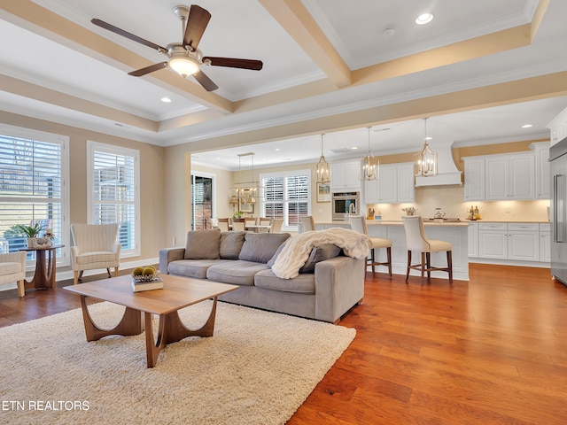 living room featuring ornamental molding, ceiling fan with notable chandelier, wood finished floors, recessed lighting, and a raised ceiling