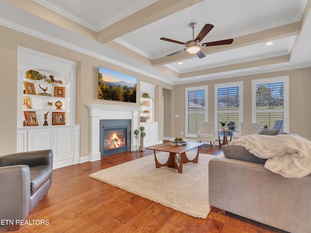 living room with a glass covered fireplace, wood finished floors, and crown molding