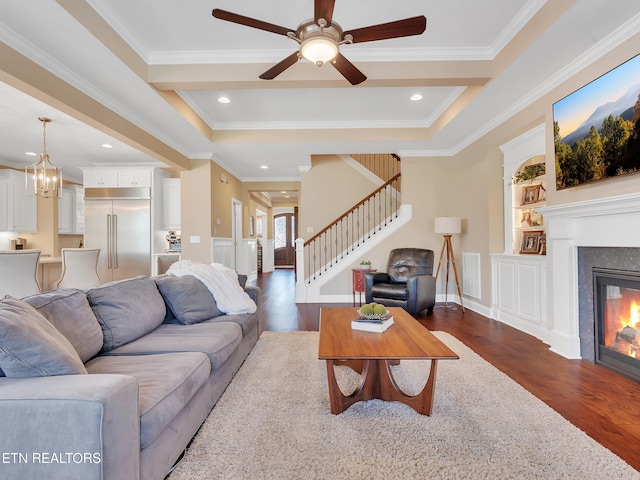 living room featuring stairway, built in shelves, dark wood-type flooring, and a glass covered fireplace