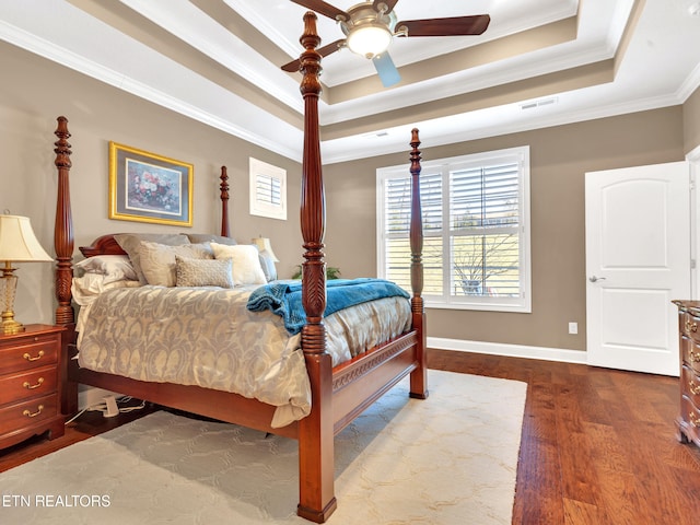 bedroom with visible vents, crown molding, a tray ceiling, and wood finished floors