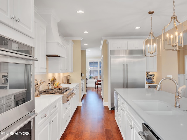 kitchen with dark wood finished floors, a sink, stainless steel appliances, light countertops, and white cabinets