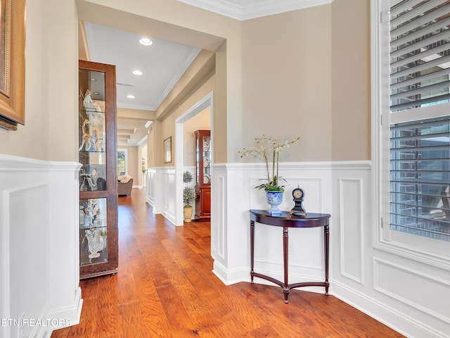 hallway featuring a decorative wall, recessed lighting, wood finished floors, and ornamental molding