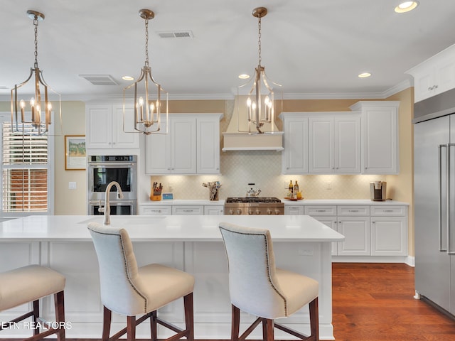 kitchen with crown molding, a kitchen breakfast bar, visible vents, and appliances with stainless steel finishes