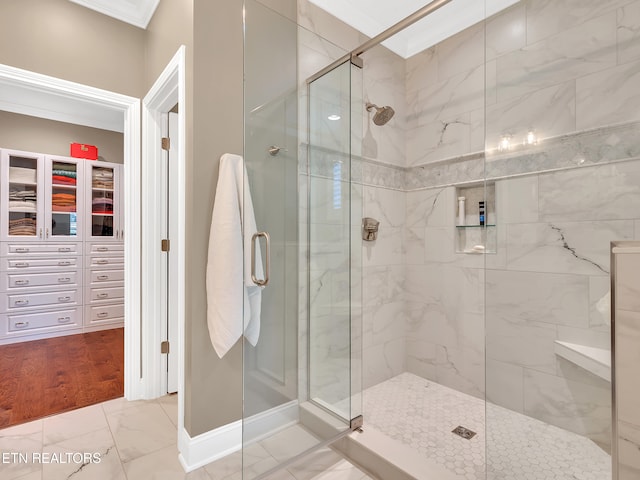 bathroom featuring a spacious closet, marble finish floor, a stall shower, and ornamental molding