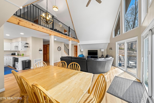 dining room with a towering ceiling, sink, a notable chandelier, and light hardwood / wood-style flooring