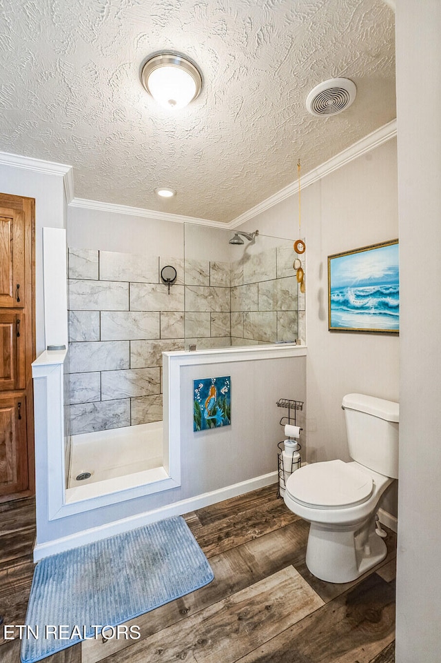 bathroom featuring visible vents, toilet, ornamental molding, wood finished floors, and a walk in shower