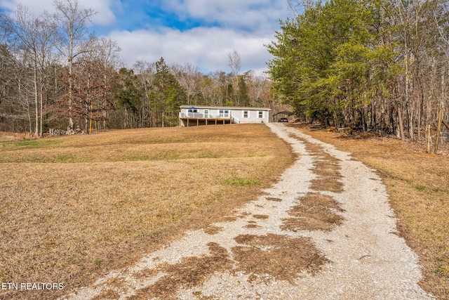 view of front of home with driveway, a front lawn, and a wooded view