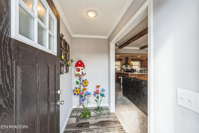 entryway with a textured ceiling, baseboards, and crown molding