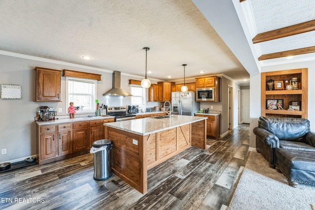 kitchen featuring a center island, hanging light fixtures, appliances with stainless steel finishes, wall chimney range hood, and a kitchen bar