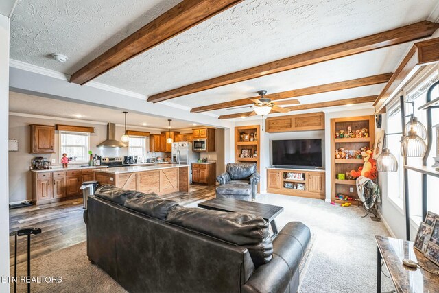 living area with a textured ceiling, a ceiling fan, beam ceiling, and baseboards