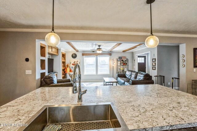 kitchen featuring pendant lighting, open floor plan, a sink, and ornamental molding