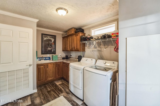 laundry area with cabinet space, dark wood-style floors, crown molding, washing machine and dryer, and a sink