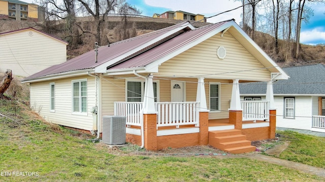 view of front of home with cooling unit, covered porch, and a front yard