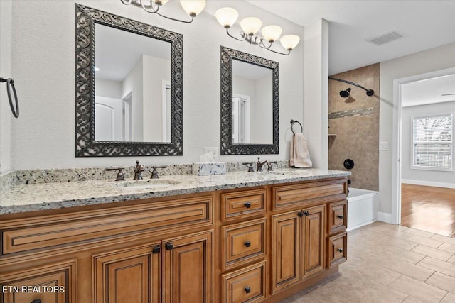 bathroom with double vanity, bathtub / shower combination, visible vents, a sink, and baseboards