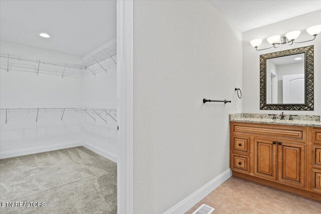 bathroom featuring visible vents, a spacious closet, vanity, and baseboards