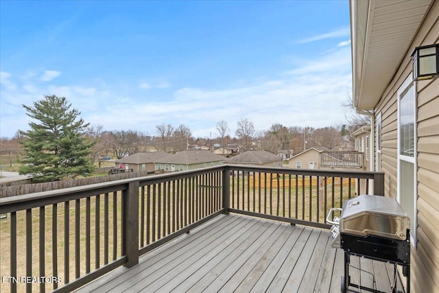 deck featuring a lawn, grilling area, fence, and a residential view