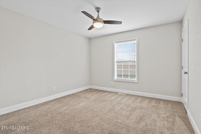 carpeted empty room featuring baseboards and a ceiling fan