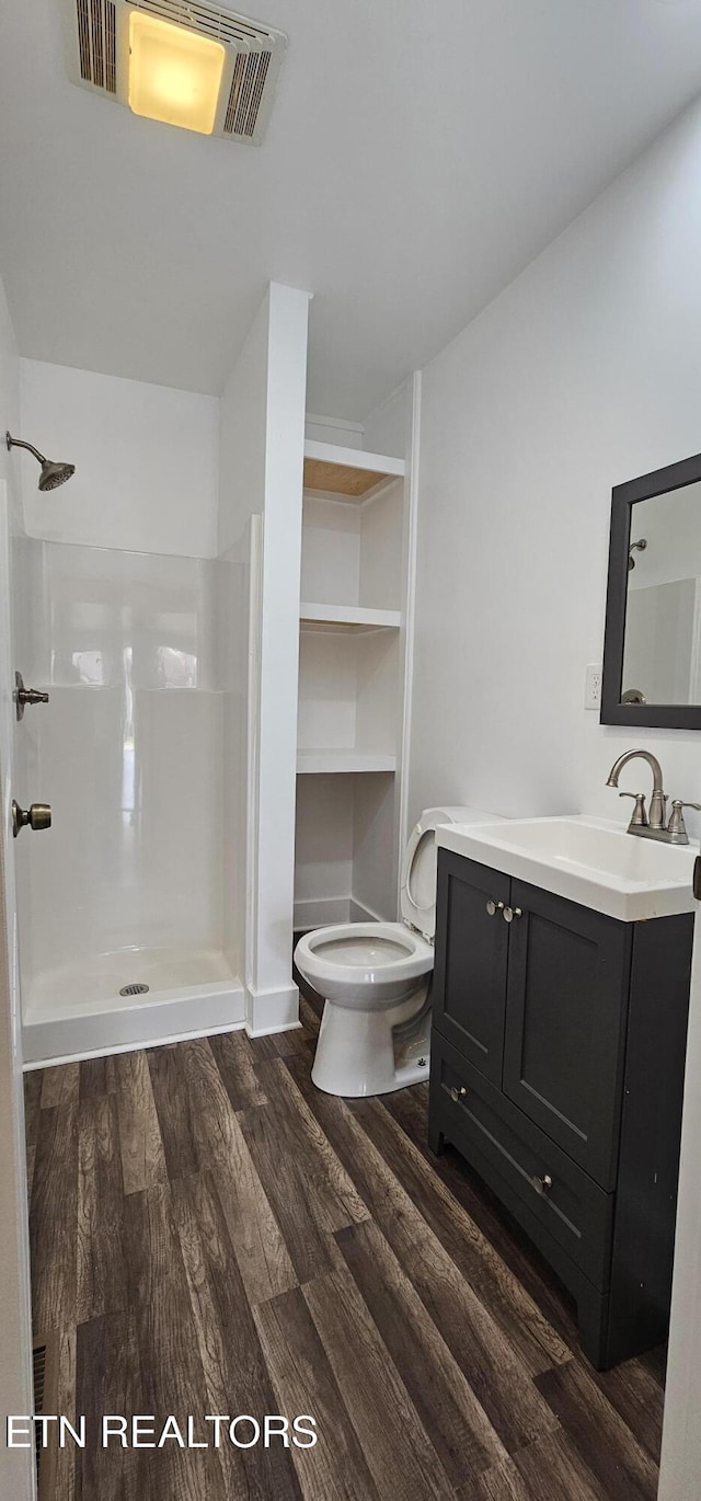 full bath with visible vents, a walk in shower, vanity, and wood finished floors