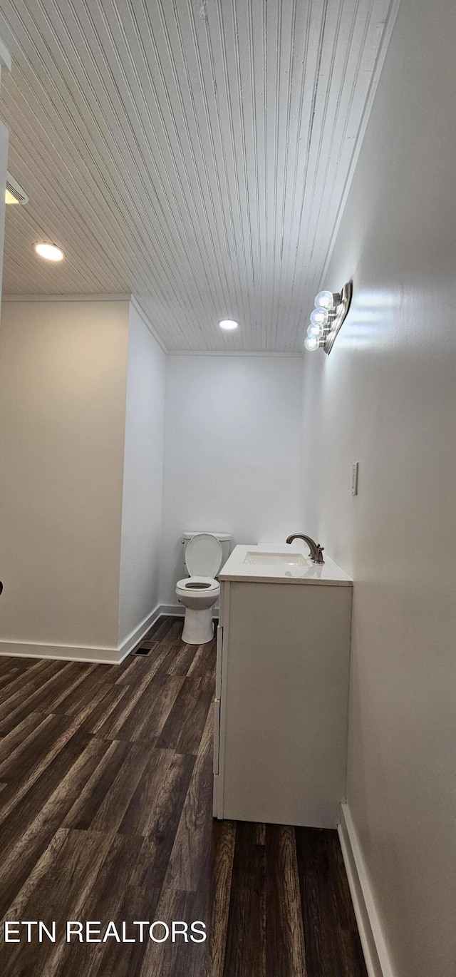 half bathroom featuring baseboards, toilet, wood finished floors, vanity, and wood ceiling