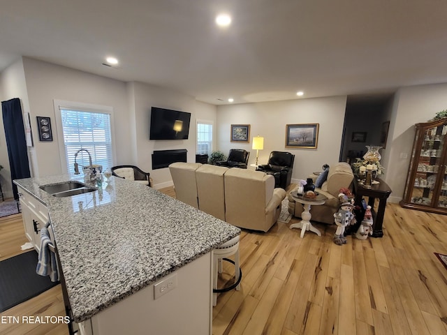 living area featuring light wood-type flooring, a healthy amount of sunlight, baseboards, and recessed lighting