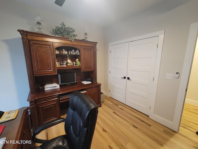 home office featuring light wood finished floors, ceiling fan, and baseboards