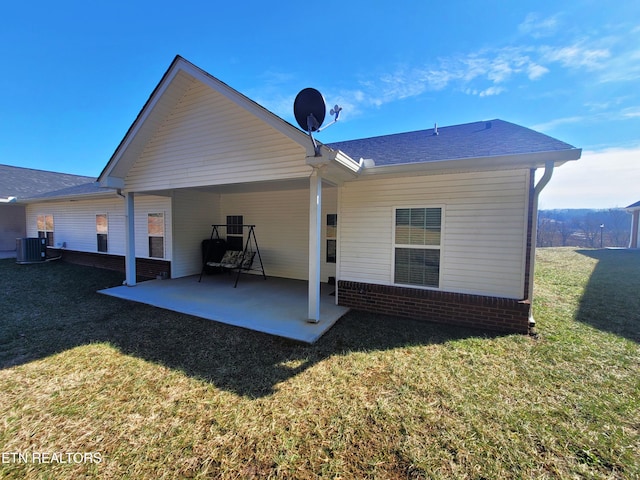 back of house featuring central air condition unit, brick siding, a patio, and a yard